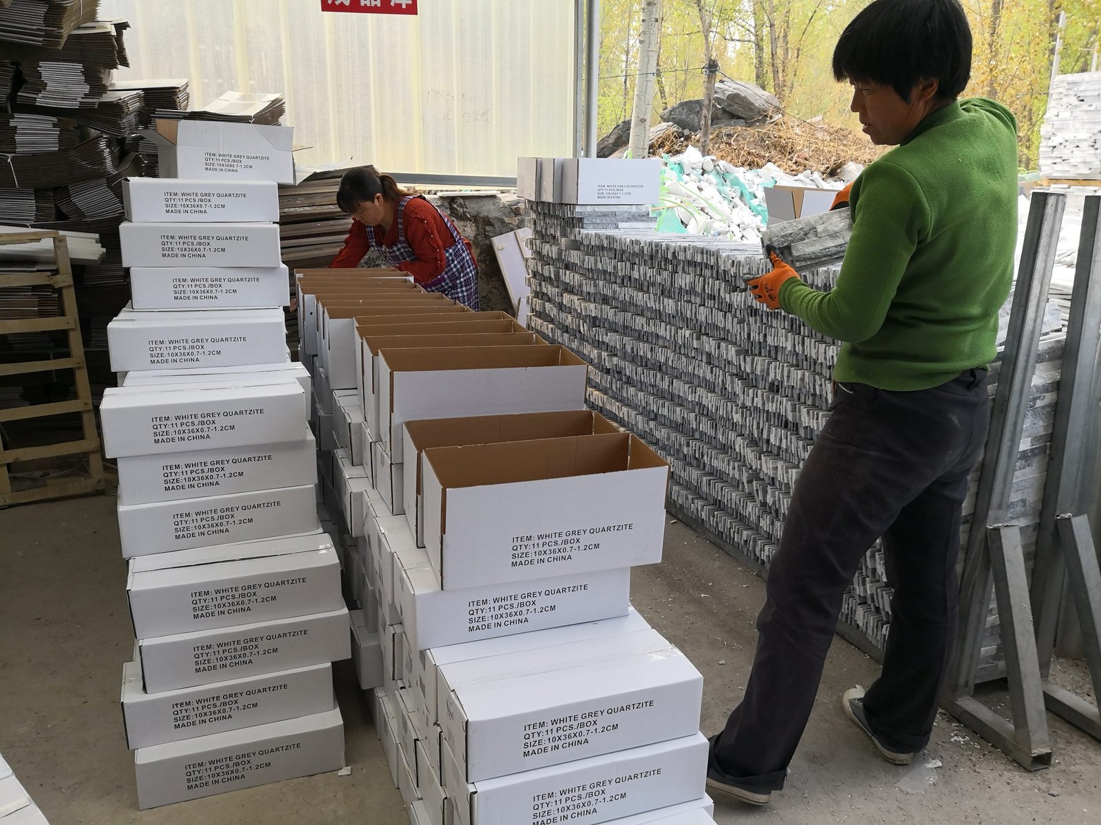 warehouse worker stacking white cartons of ledger panels