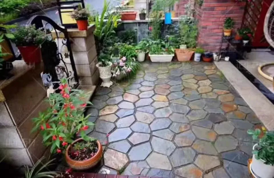 Wet hexagonal slate paving in a small planted courtyard between brick and stone walls